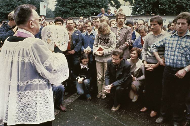 1980 Stakingsleider Lech Walesa knielt voor priester, temidden van stakers van de Lenin-fabriek 
