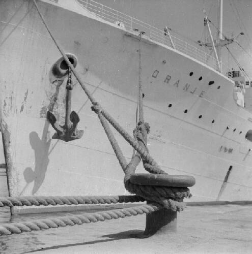 Het m.s. Oranje voor het vervoer van repatrianten aangemeerd in de haven van Tan…